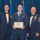 Airman Leadership School distinguished graduate Three United States Air Force personnel pose for a formal photograph at what appears to be an Airman Leadership School graduation ceremony. The central figure holds a framed diploma from the United States Air Force Airman Leadership School and wears a medal around his neck. The two flanking individuals wear formal mess dress uniforms with bow ties and display multiple service ribbons and rank insignia consistent with Senior Non-Commissioned Officers.