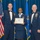 Airman Leadership School distinguished graduate Three United States Air Force personnel pose for a formal photograph at what appears to be a graduation or awards ceremony. The central figure, a female airman, holds a framed diploma from the United States Air Force Human Leadership School. The two flanking senior non-commissioned officers are dressed in formal mess dress uniforms with medals and decorations.
