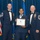 Airman Leadership School distinguished graduate Three U.S. Air Force personnel pose for a formal photograph at what appears to be an Airman Leadership School graduation ceremony. A female airman in the center holds a framed diploma from the United States Air Force Airman Leadership School. Two senior enlisted members (Chief Master Sergeants) in dress blues with bow ties flank her on either side.