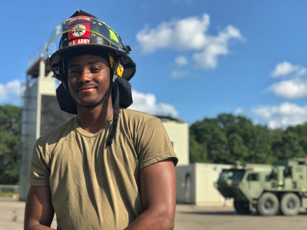 Spc. Mikail Greene stands in front of a fire training-tower