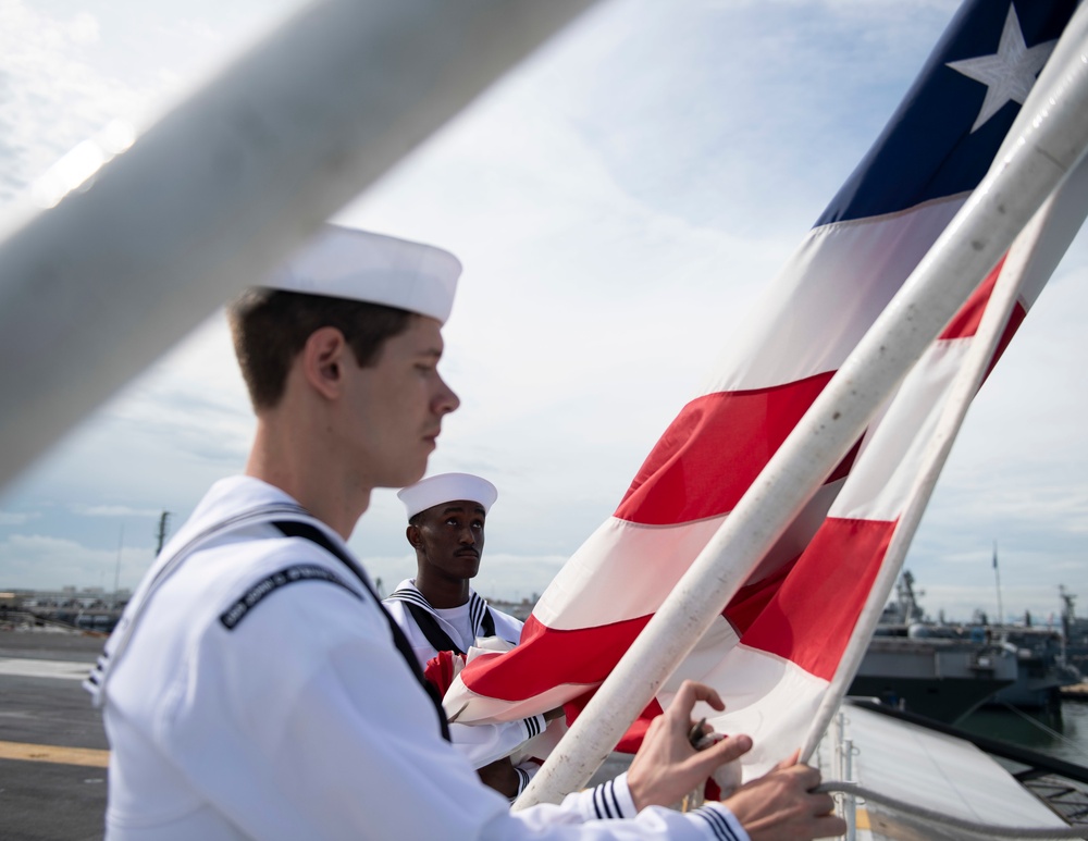 U.S. Sailors lower the American flag on the aircraft carrier USS John C. Stennis