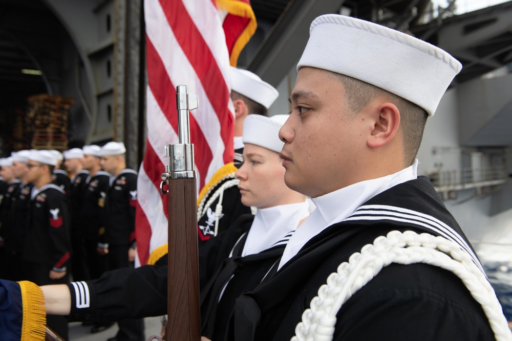U.S. Navy Aviation Electronics Technician 3rd Class Cyrille Somera, from Murrieta, California, stands at attention during a burial at sea