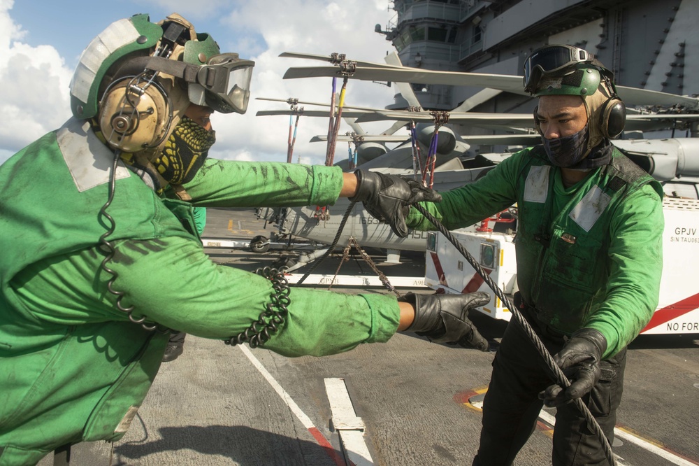 Sailors coil a cable on the flight deck