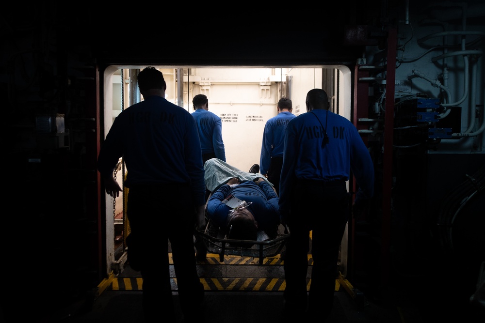 U.S. Sailors carry a simulated patient on a stretcher during a mass casualty drill