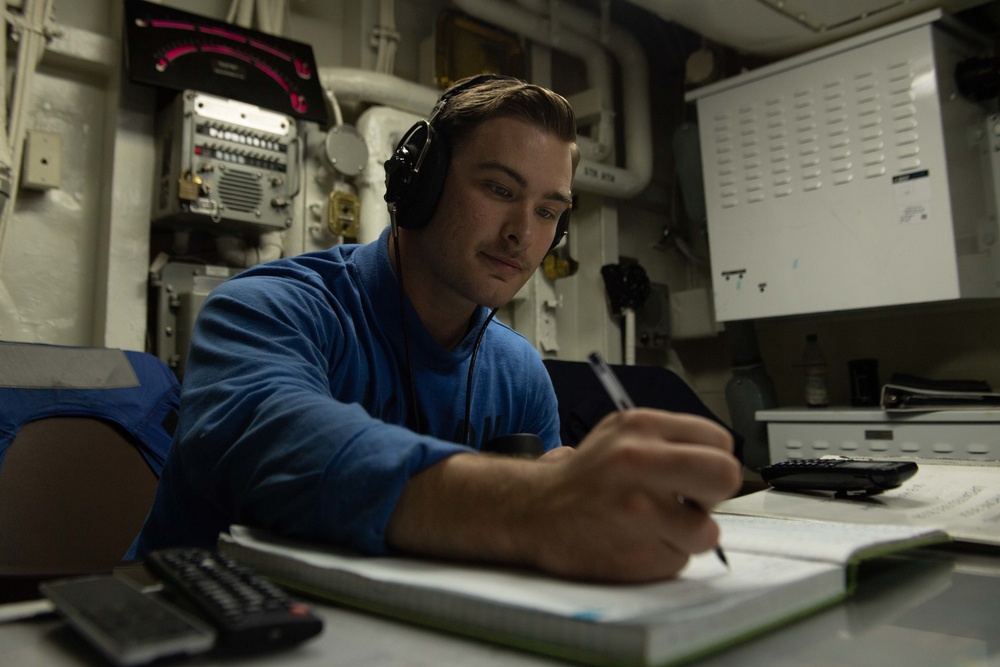U.S. Sailor logs information in a logbook in hangar deck control