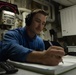 U.S. Sailor logs information in a logbook in hangar deck control
