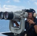 U.S. Navy Seaman Daniel Menchaca, from El Paso, Texas, looks through binoculars while on watch