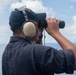U.S. Navy Seaman Daniel Menchaca, from El Paso, Texas, looks through binoculars as a lookout