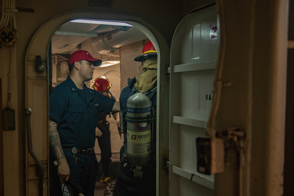 U.S. Navy Damage Controlman gives direction to the de-smoking team during a drill in the hangar bay of the aircraft carrier USS John C. Stennis