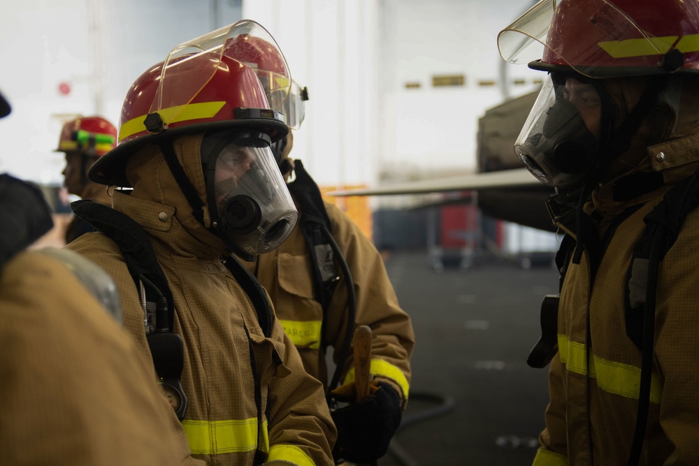 U.S. Navy Sailors complete a drill in the hangar bay of the aircraft carrier USS John C. Stennis