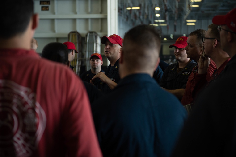 U.S. Navy Damage Controlman briefs his team after a drill in the hangar bay of the aircraft carrier USS John C. Stennis