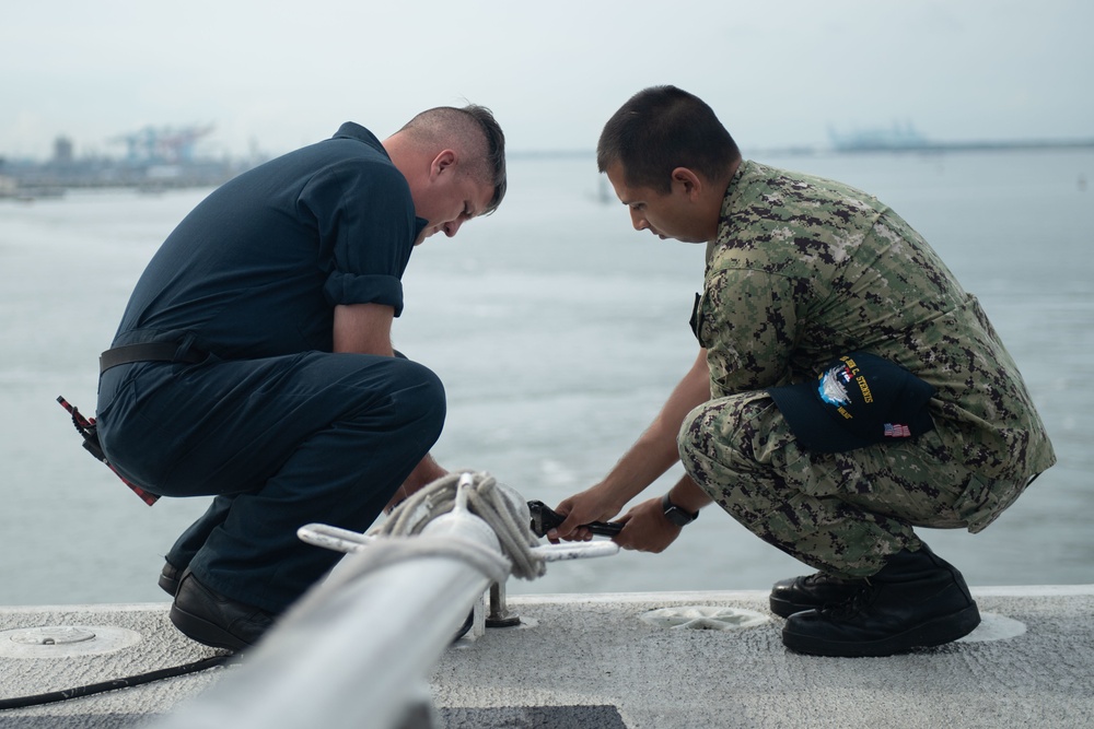 U.S. Navy Sailors lower the flag pole on the flight deck of the aircraft carrier USS John C. Stennis (CVN 74) as the ship departs Norfolk, Virginia