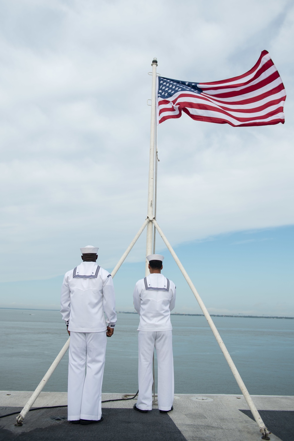 U.S. Navy Sailors prepare to lower the American flag on the flight deck of the USS John C. Stennis