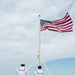 U.S. Navy Sailors prepare to lower the American flag on the flight deck of the USS John C. Stennis