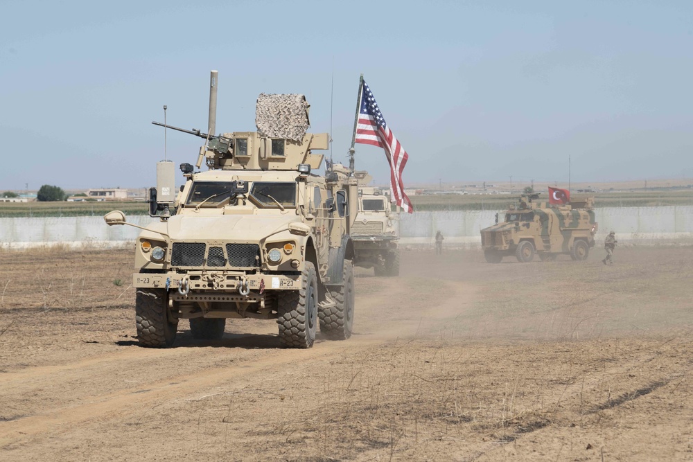 U.S. and Turkish military forces conduct a joint ground patrol inside of the security mechanism in northeast Syria