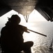 Marine sitting on the rear of a CH-53 during a flight over the ocean