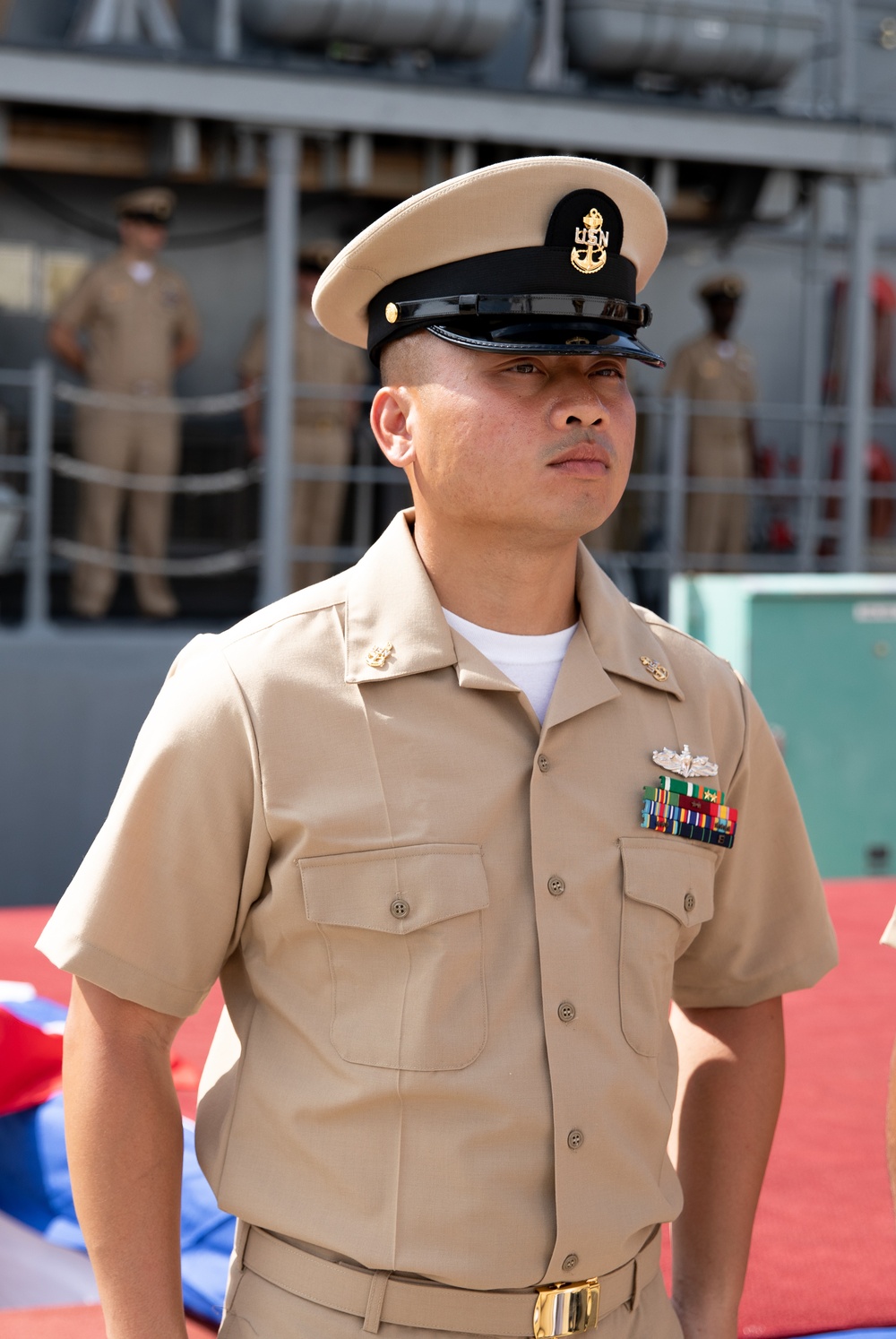 Chief Petty Officer Pua Xiong aboard Avenger-class mine countermeasures ship USS Pioneer (MCM 9), just pinned as a Chief Petty Officer, stands at attention.