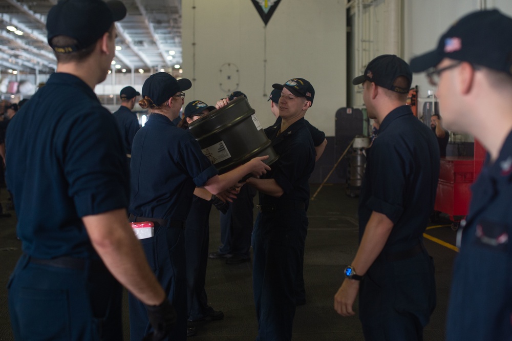 U.S. Navy Sailors pass resin barrels