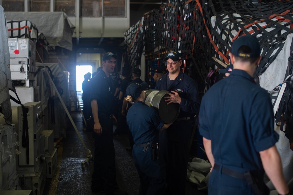 U.S. Navy Sailors pass resin barrels