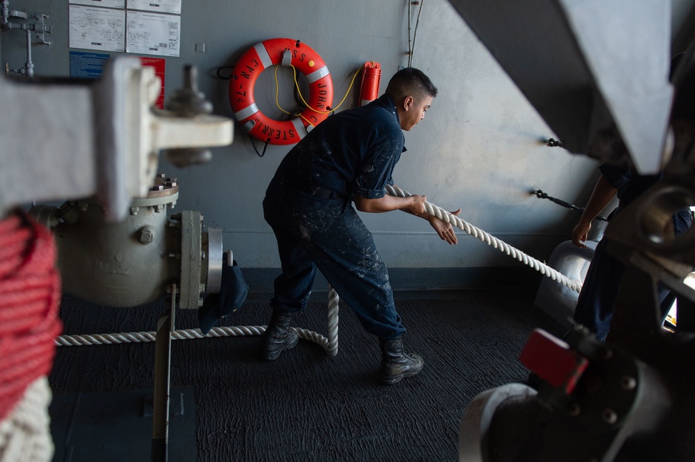 U.S. Navy Sailor heaves in a mooring line