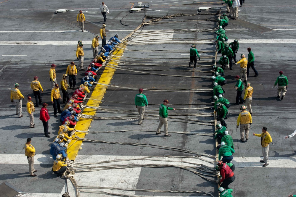 U.S. Sailors pull out a safety net during a barricade drill