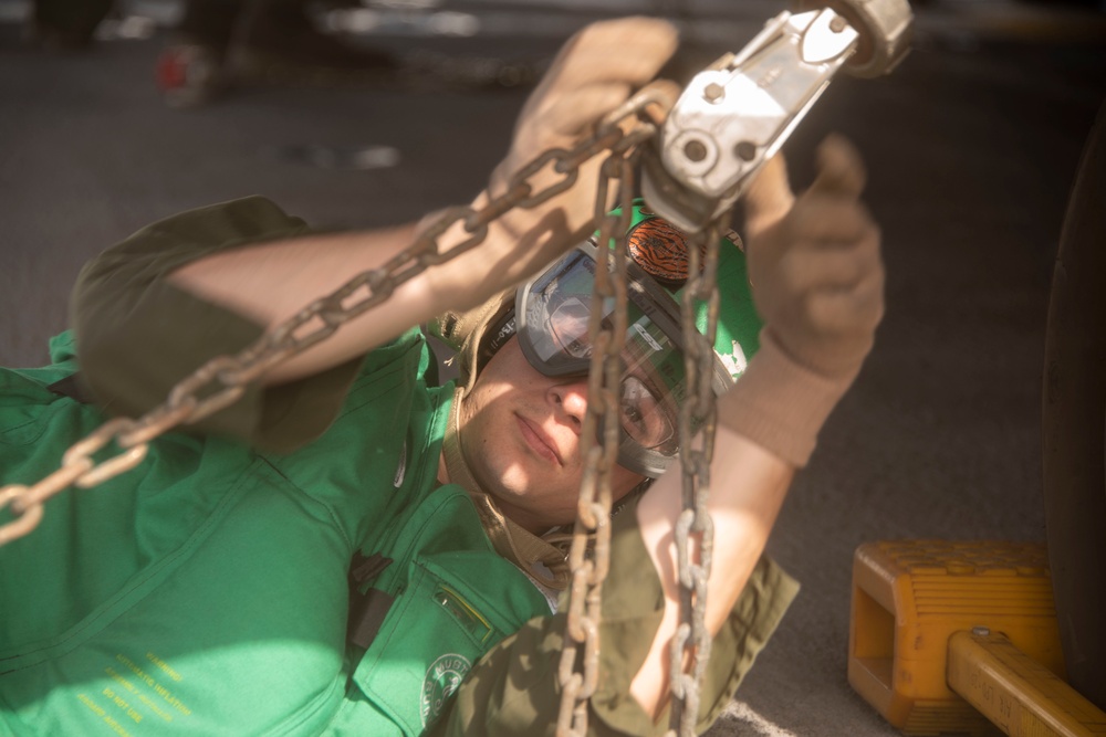 Marine tightens a chain on a Sea Stallion