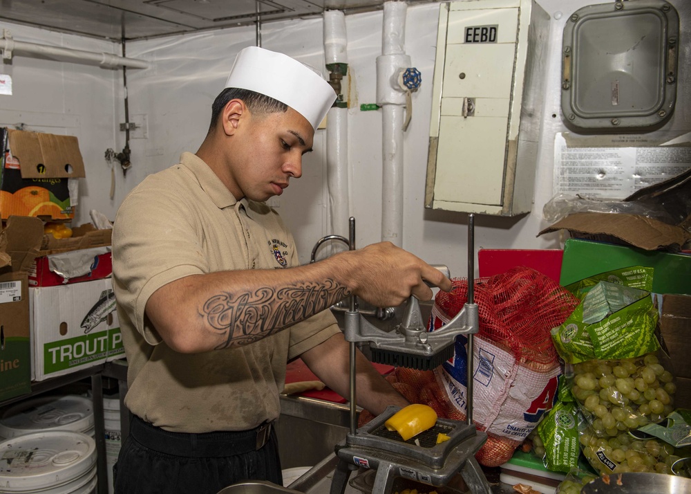 USS Normandy Sailor Chops Vegetables