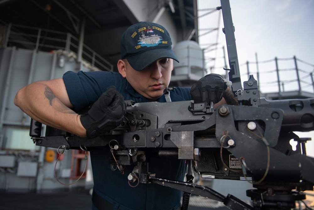 U.S. Navy Sailor conducts maintenance on a .50-caliber rifle on the fantail of the aircraft carrier USS John C. Stennis