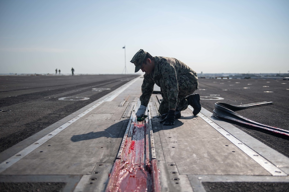 U.S. Navy Sailors cleans the catapult on the flight deck of the aircraft carrier USS John C. Stennis