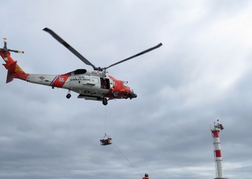 U.S. Coast Guard helicopter lowers rescue basket