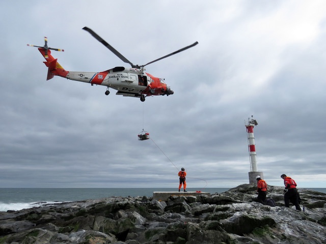 U.S. Coast Guard helicopter lowers rescue basket