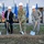 Medical facility upgrades to streamline operations A military groundbreaking ceremony featuring five individuals — four in military uniforms and one in civilian attire — all wearing white hard hats and holding ceremonial shovels over freshly turned dirt. The event takes place outdoors in front of a modern building with American and Air Force flags displayed prominently in the background. This appears to be an official U.S. military construction or facility dedication event.