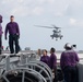 U.S. Sailors watch as a MH-60R Sea Hawk departs from the flight deck of the aircraft carrier USS John C. Stennis (CVN 74)