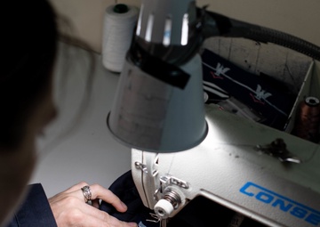 U.S. Sailor sews a rank tab onto coveralls