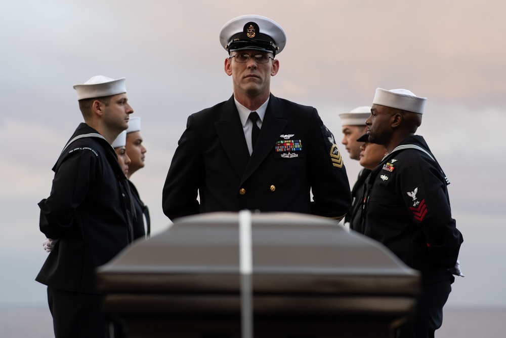 U.S. Navy Senior Chief Aviation Electronics Technichian James Hendricks, from Porum, Oklahoma, stands at parade rest during a burial at sea