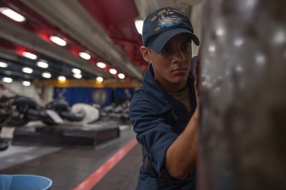 U.S. Navy Sailor sands a capsule in the fo’c’sle of the aircraft carrier USS John C. Stennis