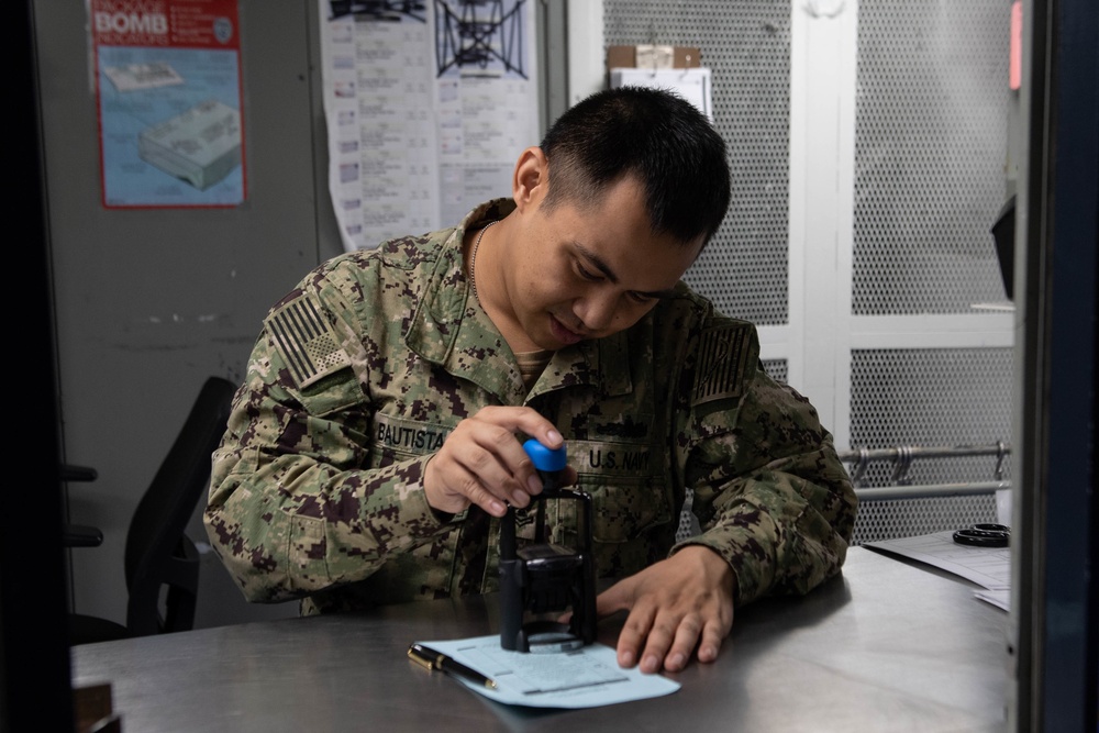 U.S. Sailor stamps a new check-in card in the post office