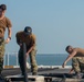 U.S. Sailors coil fuel line