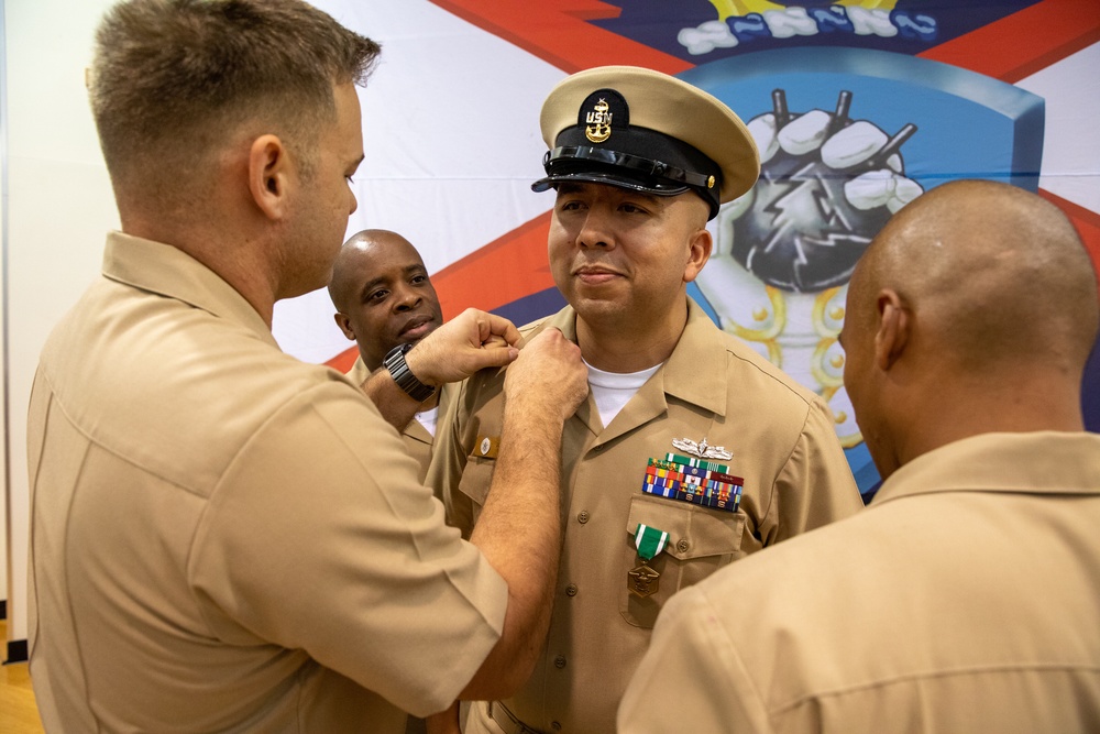 Chief Warrant Officer 2 Juan Castillo has his Senior Chief insignia removed by his fellow chiefs as part of his officer commissioning ceremony