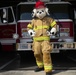 Sparky stands in front of a fire truck.