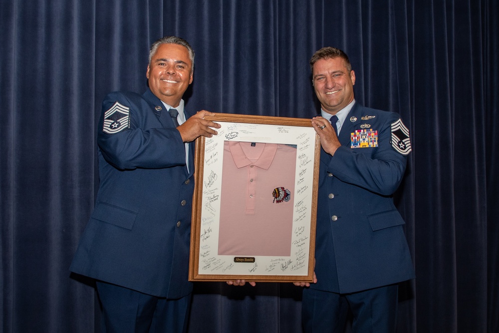 Chief Master Sgt. Cameron Pieters hands off the pink polo to Chief Master Sgt. Shawn Plunket
