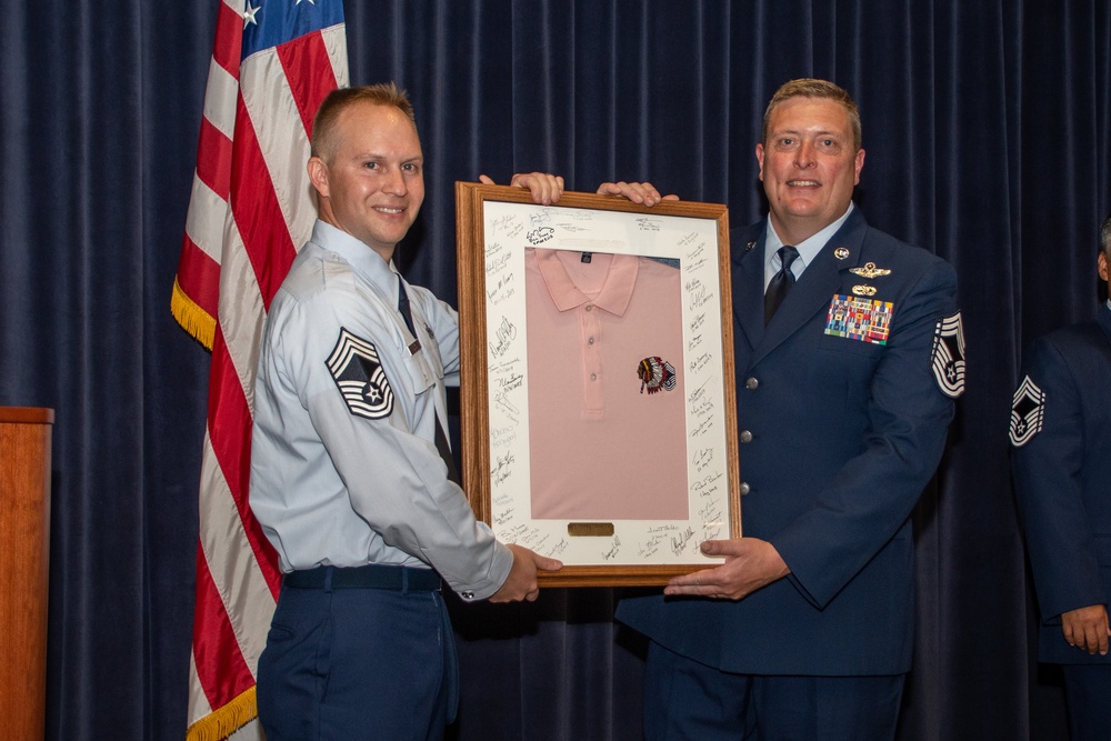 Chief Master Sgt. Jeffrey Linton hands off the pink polo to Chief Master Sgt. Todd Houchens