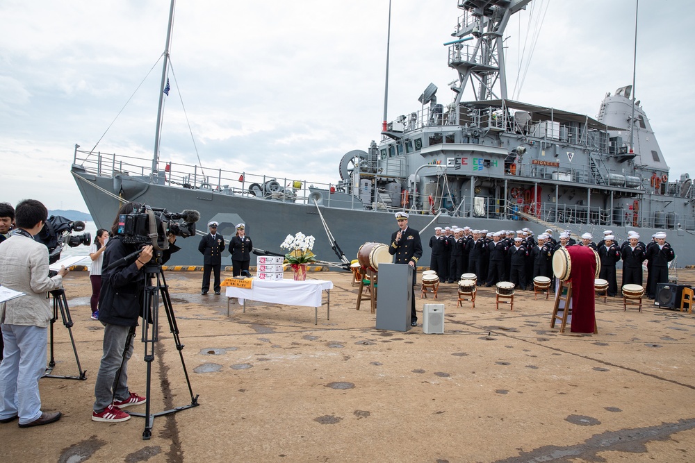 USS Pioneer (MCM 9) commanding officer gives opening remarks during a ceremony in Uki city, Japan