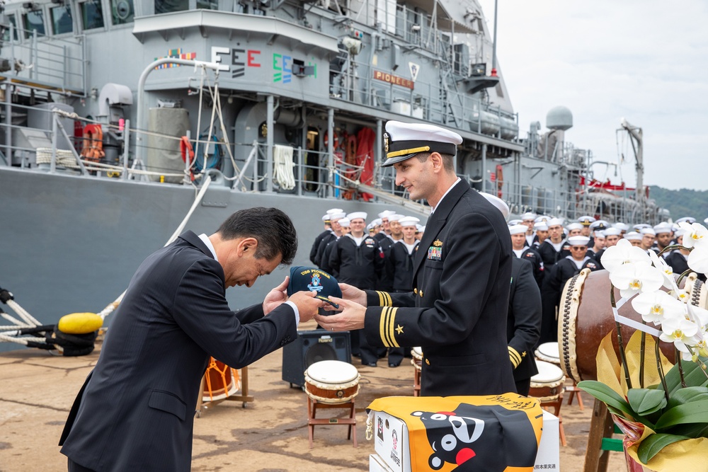 USS Pioneer (MCM 9) commanding officer gives a ball cap to the mayor of Uki city during Pioneer’s arrival ceremony