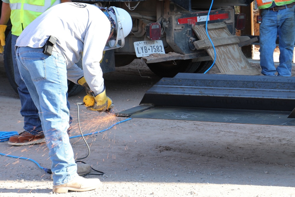 Task Force Barrier contractor prepares a steel bollard barrier panel for placement in Columbus, N.M.