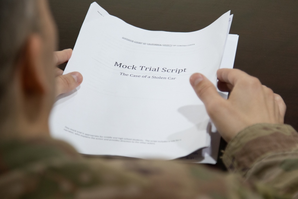 Maj. Joshua Dimkoff reads the script for a mock trial