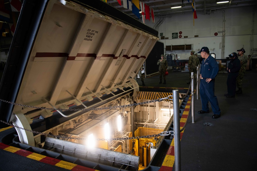 U.S. Sailors lower an industrial elevator on the hangar bay