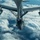 An aerial photograph taken from a tanker aircraft showing a B-52 Stratofortress bomber during an air-to-air refueling operation. The image is captured from the boom operator's perspective looking down at the receiving aircraft against a backdrop of clouds and blue sky. Partial markings on the tanker's wing are visible, including the number '100' and partial text 'ARW' (Air Refueling Wing).