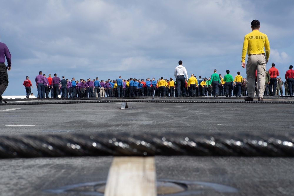 U.S. Sailors muster at the bow of the flight deck for a foreign object debris (FOD) walkdown