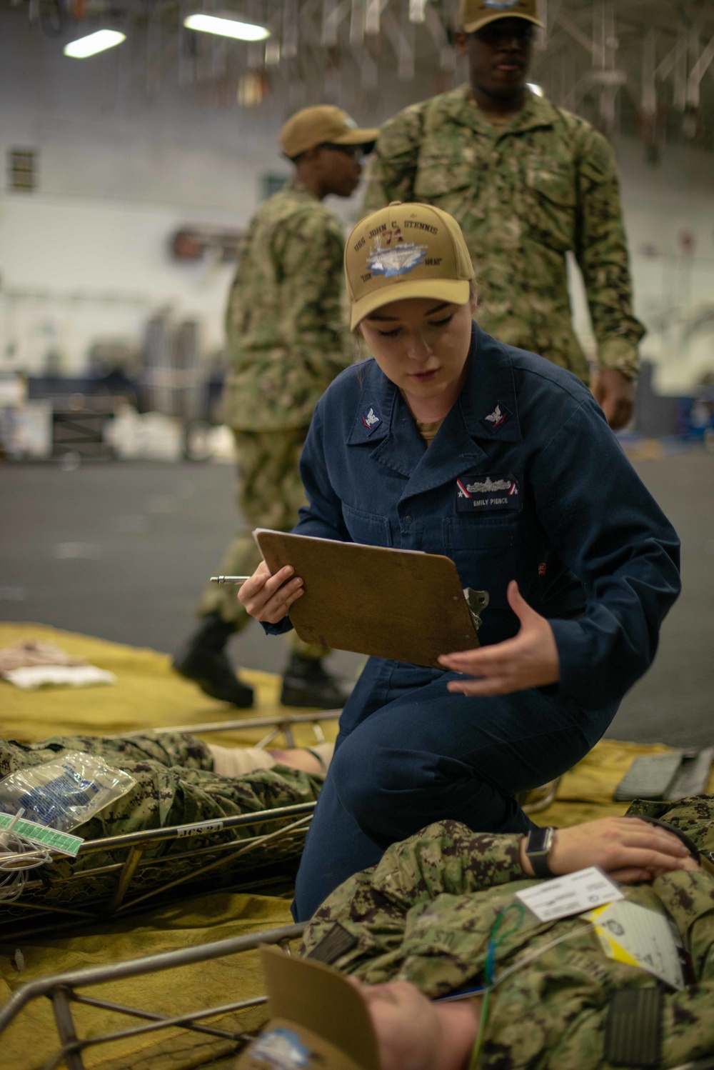 U.S. Navy Hospital Corpsman 3rd Class Emily Pierce, from Bremerton, Washington, checks on a simulated patient during a mass casualty drill